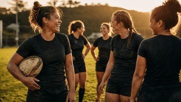 Women rugby players celebrating together on the pitch after rugby training.