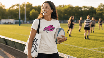 Women's rugby mom on sideline in graphic tee with tote and ball