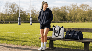 Woman rugby player on pitch bench comparing durable canvas rugby tote bag versus duffel bag