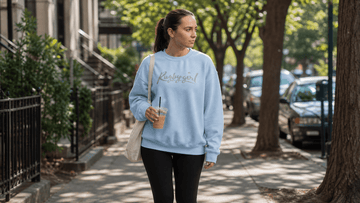 Woman in sporty casual rugby sweatshirt and leggings walking sunny city sidewalk