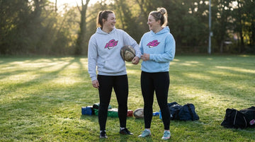 Two women comparing women's rugby hoodie sizing in graphic RG Impact hoodies