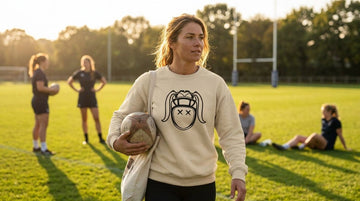 Woman on pitch in sand Harlequin sweatshirt carrying ball RugbyGirl collection review