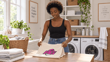 Woman folding a beige graphic rugby tee with RG Impact print after washing