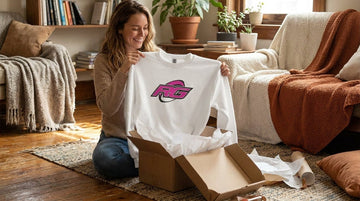 Woman unboxing white RG Impact rugby sweatshirt gift apparel that gets worn