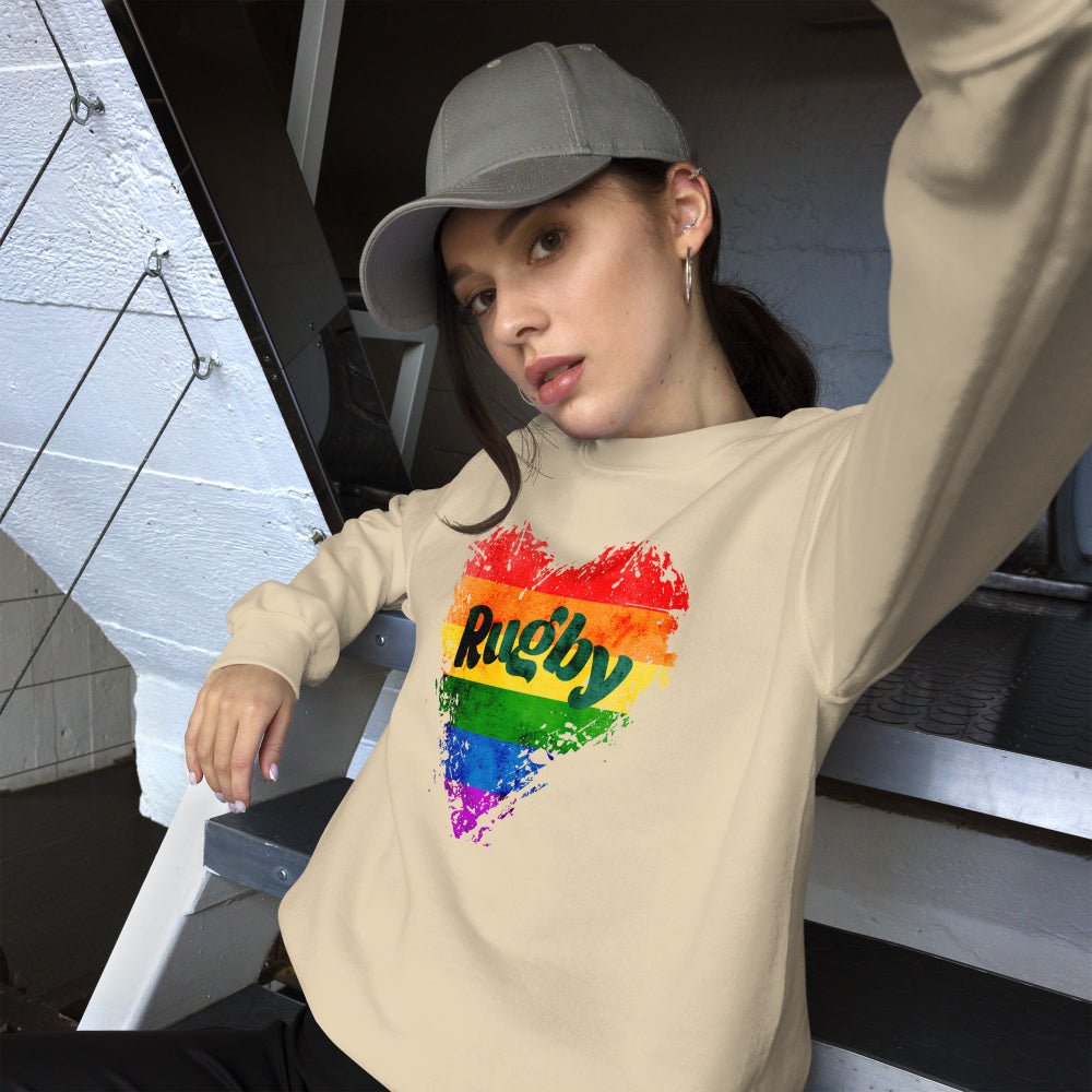 Women's sand colored sweatshirt with rainbow heart and bold "Rugby" text, casual rugby apparel. - Rugby Girl